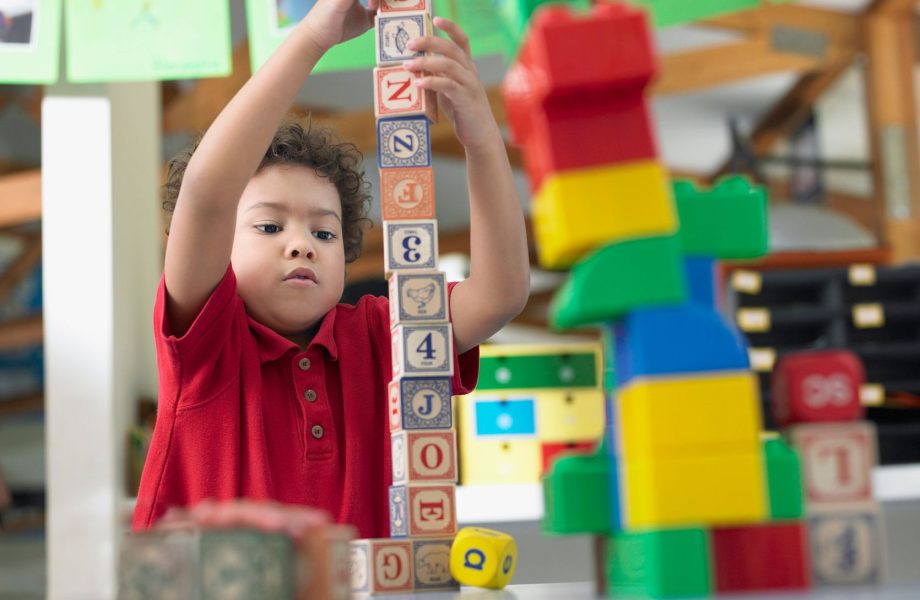Preschool child learning through playing with stacking blocks.